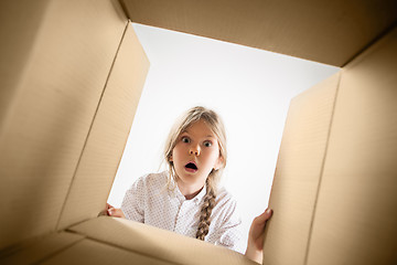 Image showing The girl unpacking and opening carton box and looking inside