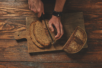 Image showing Baker man slices bread