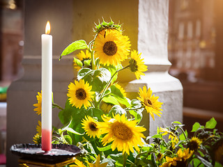 Image showing sunflowers with a burning candle in a church