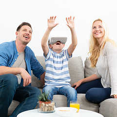 Image showing Happy family at home on living room sofa having fun playing games using virtual reality headset