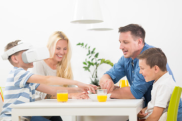 Image showing Happy family at home on living room sofa having fun playing games using virtual reality headset