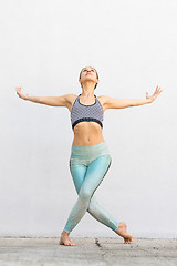 Image showing Fit sporty active girl in fashion sportswear doing yoga fitness exercise in front of gray wall, outdoor sports, urban style