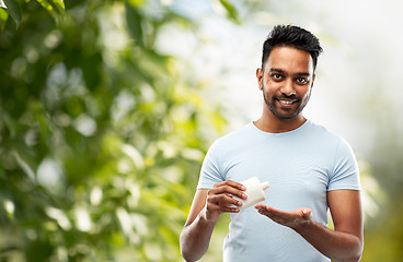 Image showing happy indian man applying lotion to his hand