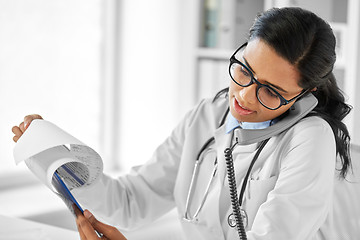 Image showing doctor with clipboard calling on phone at hospital