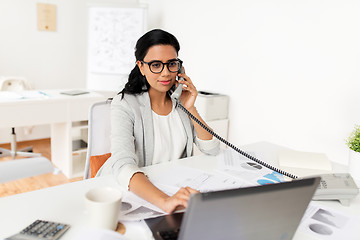 Image showing businesswoman calling on desk phone at office