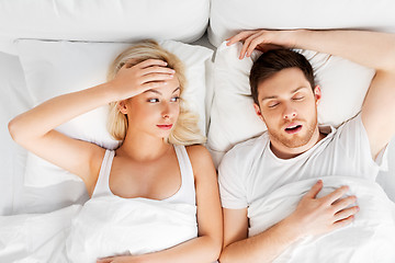 Image showing unhappy woman in bed with snoring sleeping man