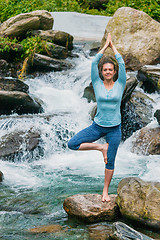 Image showing Woman in yoga asana Vrikshasana tree pose at waterfall outdoors