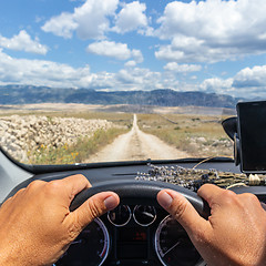 Image showing Detail of male driver hands on steering wheel. Driving a car on country road. View from the cabin trough the windshield.