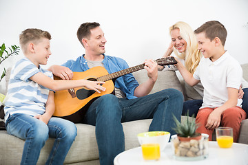 Image showing Happy caucasian family smiling, playing guitar and singing songs together at cosy modern home