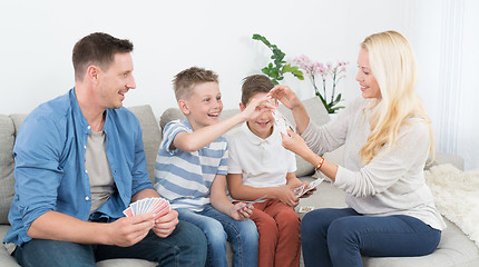 Image showing Happy young family playing card game at home.