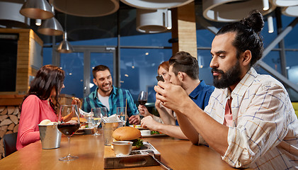 Image showing man messaging on smartphone at restaurant