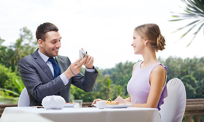 Image showing man photographing woman by camera at restaurant