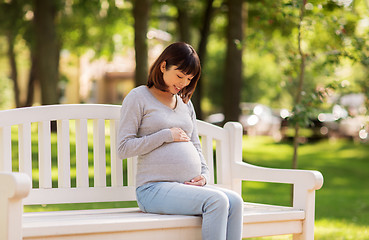 Image showing happy pregnant asian woman sitting on park bench