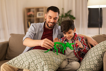 Image showing father and son playing with toy dinosaur at home