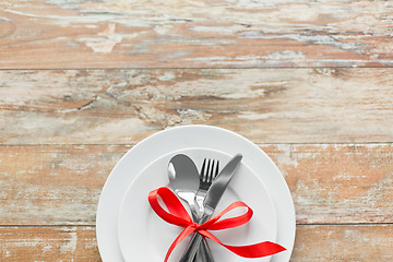 Image showing cutlery tied with red ribbon on set of plates