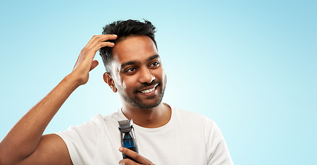 Image showing smiling indian man with trimmer touching his hair