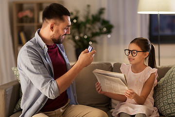 Image showing father photographing daughter by cellphone at home