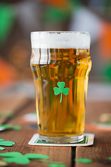 Image showing close up of glass of beer with shamrock on table