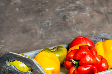 Image showing Imperfect natural peppers and tomatoes on an old wooden tray on a dark background. Copy Space.