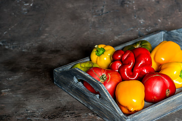 Image showing Imperfect natural peppers and tomatoes on an old wooden tray on a dark background. Copy Space.