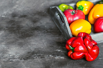 Image showing Imperfect natural peppers and tomatoes on an old wooden tray on a dark background. Copy Space.