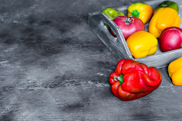 Image showing Imperfect natural peppers and tomatoes on an old wooden tray on a dark background. Copy Space.