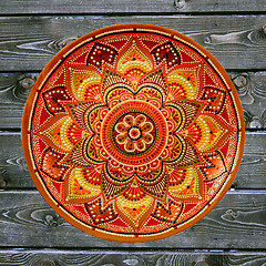 Image showing Decorative ceramic plate, hand painted dot pattern with acrylic paints on a gray wooden background. A square photo. Closeup.