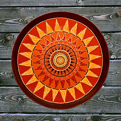 Image showing Decorative ceramic plate, hand painted dot pattern with acrylic paints on a gray wooden background. A square photo. Closeup.