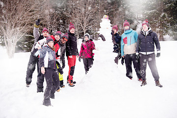 Image showing group portait of young people posing with snowman