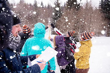 Image showing young people measuring the height of finished snowman