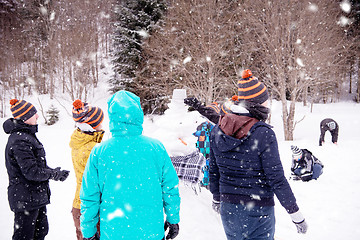 Image showing group of young people making a snowman