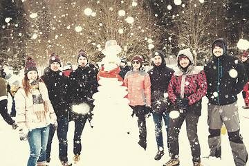 Image showing group portait of young people posing with snowman