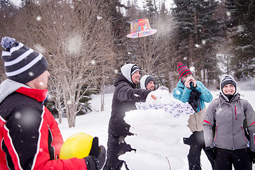 Image showing group of young people making a snowman