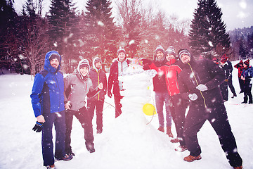 Image showing group portait of young people posing with snowman