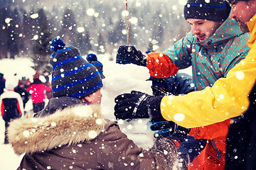 Image showing group of young people making a snowman