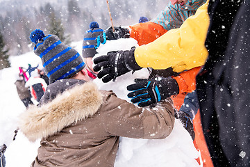 Image showing group of young people making a snowman