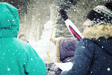 Image showing young people measuring the height of finished snowman