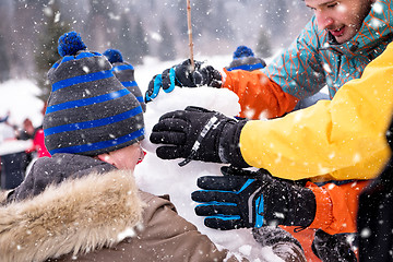 Image showing group of young people making a snowman