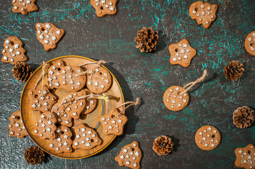 Image showing Christmas theme with cookies, spruce cones on a dark background. Flat lay.