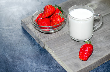 Image showing Fresh strawberries and milkshake on a wooden on wooden boards