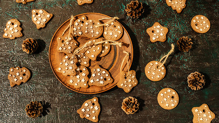 Image showing Christmas theme with cookies, spruce cones on a dark background. Flat lay.