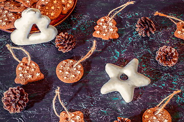 Image showing Christmas theme with cookies, spruce cones on a dark background. Flat lay.