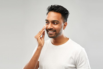 Image showing smiling indian man cleaning face with cotton pad