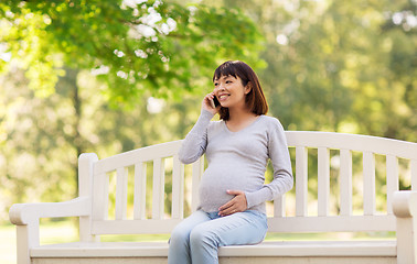 Image showing pregnant asian woman calling on smartphone at park