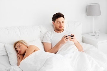 Image showing man using smartphone while woman is sleeping