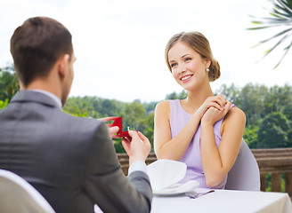 Image showing man giving woman engagement ring at restaurant