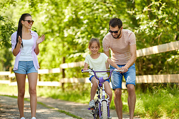 Image showing kid with patents learning to ride bicycle in park