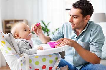 Image showing father feeding happy baby in highchair at home