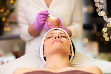 Image showing beautician applying facial mask to woman at spa