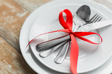 Image showing close up of cutlery tied with red ribbon on plates